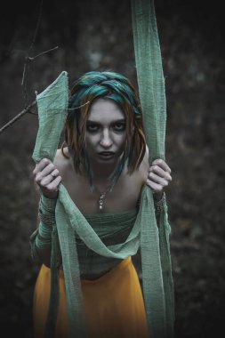 Sonbahar yeşili içinde yeşil ve sarı cüppeli ölü bir kız.