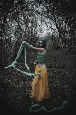 Sonbahar yeşili içinde yeşil ve sarı cüppeli ölü bir kız.