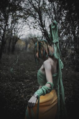 Sonbahar yeşili içinde yeşil ve sarı cüppeli ölü bir kız.
