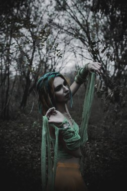 Sonbahar yeşili içinde yeşil ve sarı cüppeli ölü bir kız.