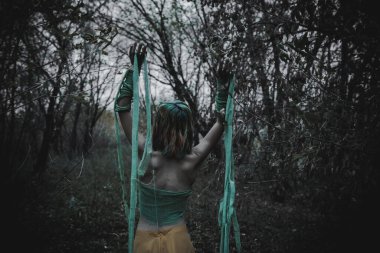 Sonbahar yeşili içinde yeşil ve sarı cüppeli ölü bir kız.