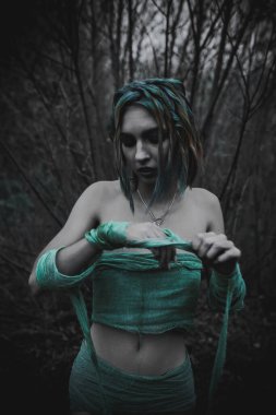 Sonbahar yeşili içinde yeşil ve sarı cüppeli ölü bir kız.