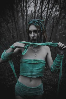 Sonbahar yeşili içinde yeşil ve sarı cüppeli ölü bir kız.