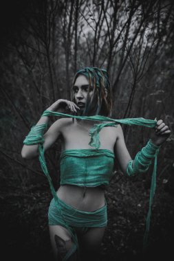 Sonbahar yeşili içinde yeşil ve sarı cüppeli ölü bir kız.