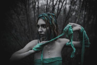 Sonbahar yeşili içinde yeşil ve sarı cüppeli ölü bir kız.