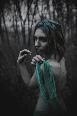 Sonbahar yeşili içinde yeşil ve sarı cüppeli ölü bir kız.