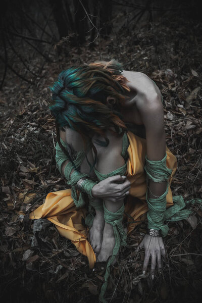 мертвая девушка в осенней листве в зеленых и желтых одеждах