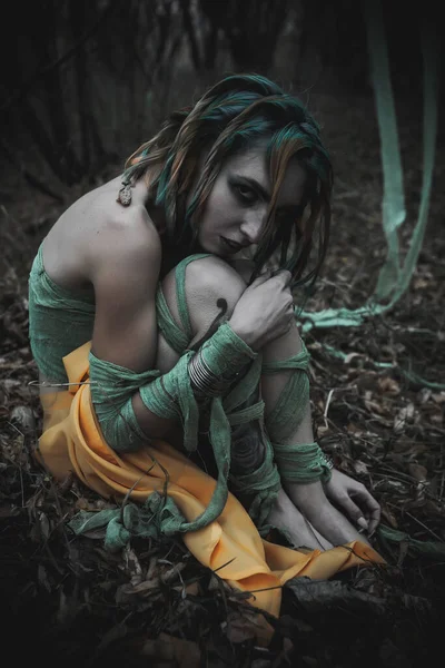 Sonbahar yeşili içinde yeşil ve sarı cüppeli ölü bir kız.