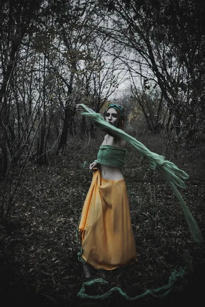 Sonbahar yeşili içinde yeşil ve sarı cüppeli ölü bir kız.