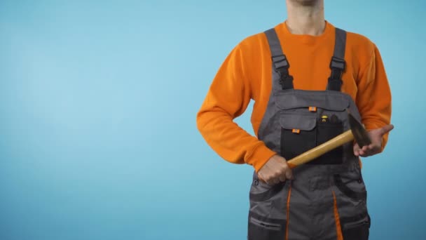 Muž s pracovním oděvem a kladivem v ruce stojí na pravé s kopírovat prostor koncept — Stock video