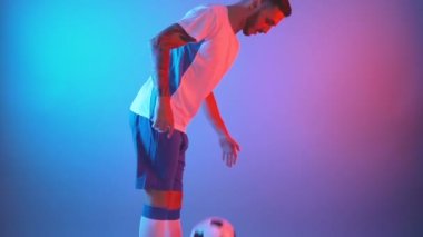 Serbest stil futbolcunun bacaklarıyla ve dizleriyle topu hokkabazlık yaparken yan görünümü