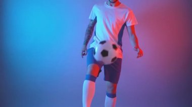 Profesyonel futbolcu bacaklarıyla ve dizleriyle top oynuyor.