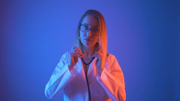 Belle femme médecin avec des lunettes et manteau blanc décoller stéthoscope des épaules et commencer à écouter — Video