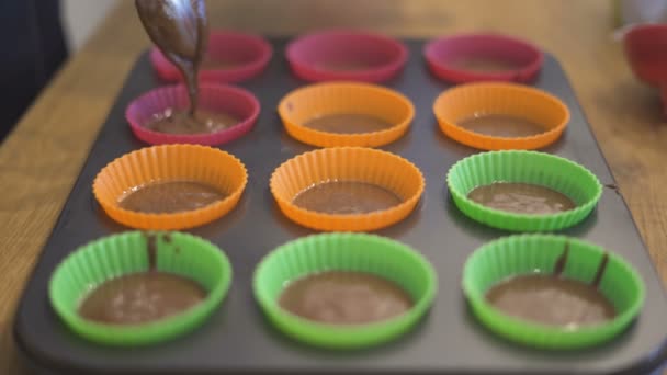 Chefs mãos com colher encher chocolate para assar muffins em copos de papel — Vídeo de Stock