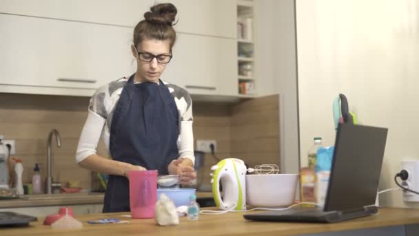Giovane donna in grembiule in piedi in cucina e preparare il cibo per la sua famiglia — Video Stock