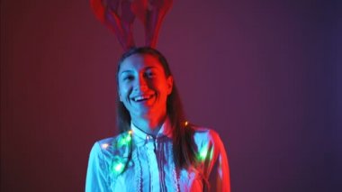 Noel ışıkları ve geyik boynuzlarıyla dans eden güzel genç bir kadın.