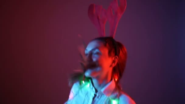 Noel havasında genç bir kadın ren geyiği boynuzu takıyor ve dans ediyor. — Stok video