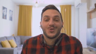 Evde çalışan kulaklıklı ve web kameralı bir gencin görüntüsü.
