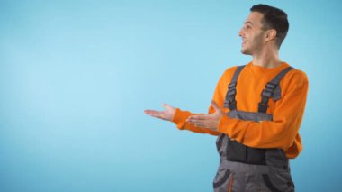 Heyecanlı işçi tulumlu inşaat işçisi sol taraftaki ürünü telif alanıyla sunuyor.