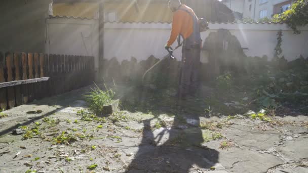 Професійний садівник використовує струнний тример для різання трави — стокове відео