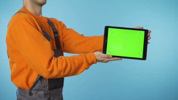 Byggarbetare i overaller som presenterar en produkt på greenscreen tablett — Stockvideo