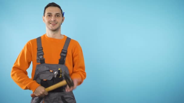 Усміхнений будівельник тримає молоток в руках, готовий допомогти — стокове відео
