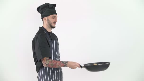 Молодой шеф-повар перелистывает овощи в воке в замедленной съемке на белом фоне — стоковое видео
