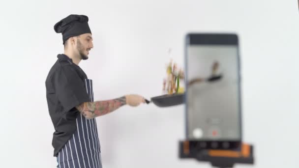 Professionell manlig kock kastar grönsaker i wok under online lektion. — Stockvideo