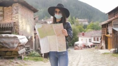 Coronavirüs salgınından sonra tatil. Turist kız harita keşfediyor ve maske takıyor.
