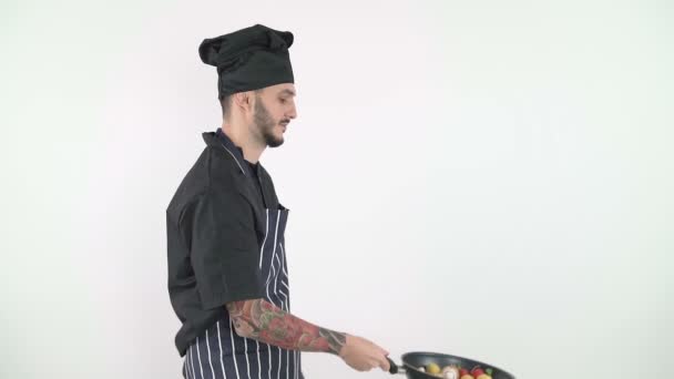 Sidovy av professionell kock kasta grönsaker i en wok mot vit bakgrund — Stockvideo