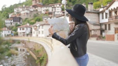 Eski kasabadaki köprüde oturan ve haritayı keşfeden kadın gezginin yan görüntüsü