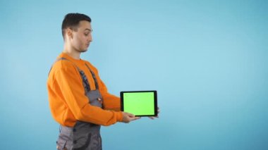 Mutlu adam, elinden her iş gelen adam mavi arka planda tablet tutuyor.