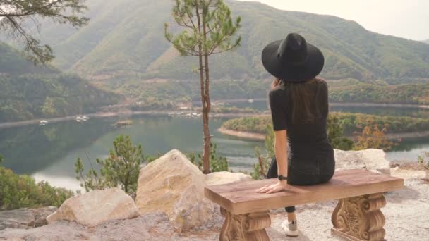 Osamělá žena sedí na lavičce a těší klidný výhled na hory — Stock video