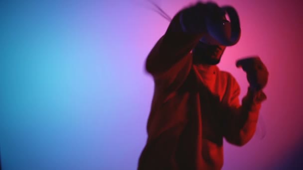 Jeune homme avec des lunettes VR montées sur la tête combattant en réalité virtuelle, faisant uppercut et gagner — Video