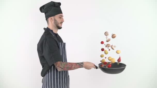 Мужчина шеф-повар бросает овощи с вока на белом фоне — стоковое видео