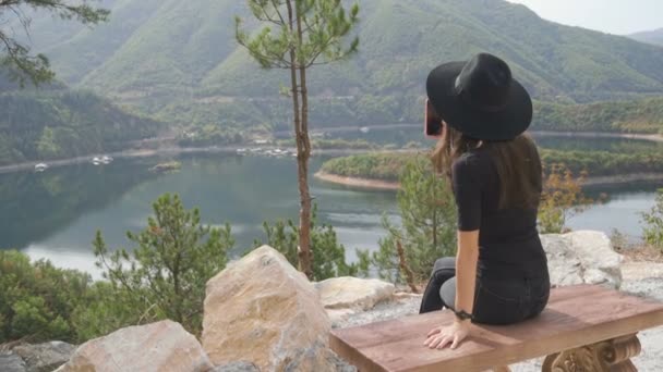 Žena sedící na lavičce pozoruje jezero. — Stock video