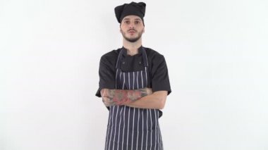 Ciddi dövmeli, üniformalı, kollarını kavuşturup kameraya bakan bir şef.