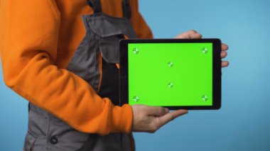 Elinden her iş gelen adamın elinde yeşil ekranlı bir tablet tutarken yakın plan fotoğrafı..