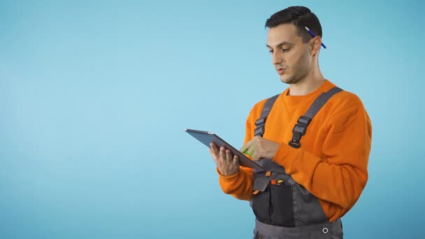 Pekerja konstruksi dengan pena di belakang telinga mencatat pada tablet, ruang penyalinan — Stok Video