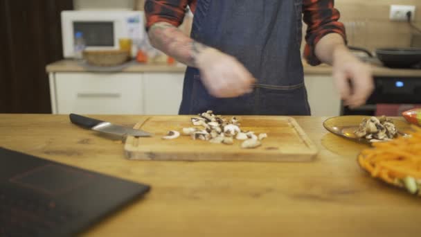 Close shot van chef-kok handen hakken champignons op een houten snijplank — Stockvideo