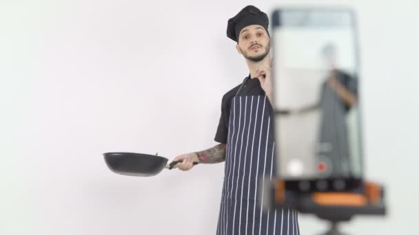 Bucătar atractiv de sex masculin în uniformă neagră și șorț ținând tigaie și streaming lecție on-line — Videoclip de stoc