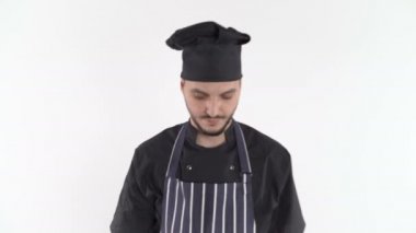Üniformalı ciddi bir aşçı beyaz arka planda kameraya yakından bakıyor.
