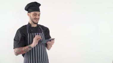 Üniformalı şef beyaz arka planda akıllı telefondan yazı yazıyor.