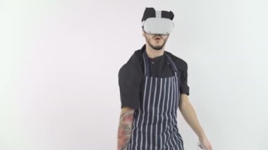 Şef üniformalı ve önlüklü genç adam VR gözlükleriyle oyun oynuyor.