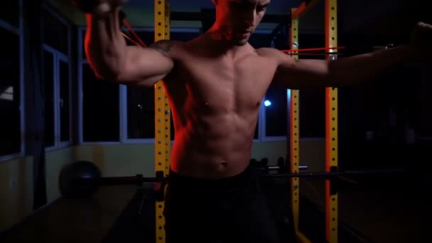 Pria atletik dengan tubuh yang sempurna melakukan latihan dengan band resistensi — Stok Video