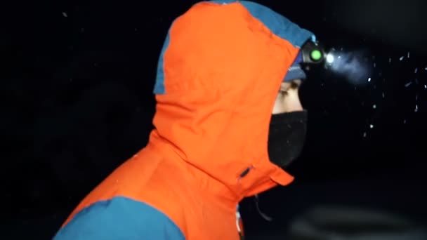 Turysta odkrywa śnieżną górę w nocy z reflektorem — Wideo stockowe