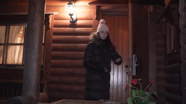 Donna in piedi all'ingresso di una baita in mezzo a un paesaggio invernale — Video Stock