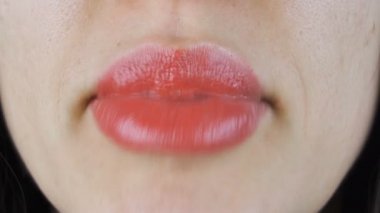 Dişi dudaklar öpüşür, konuşur ve gülümser. Kadın ağzının makro çekimi.