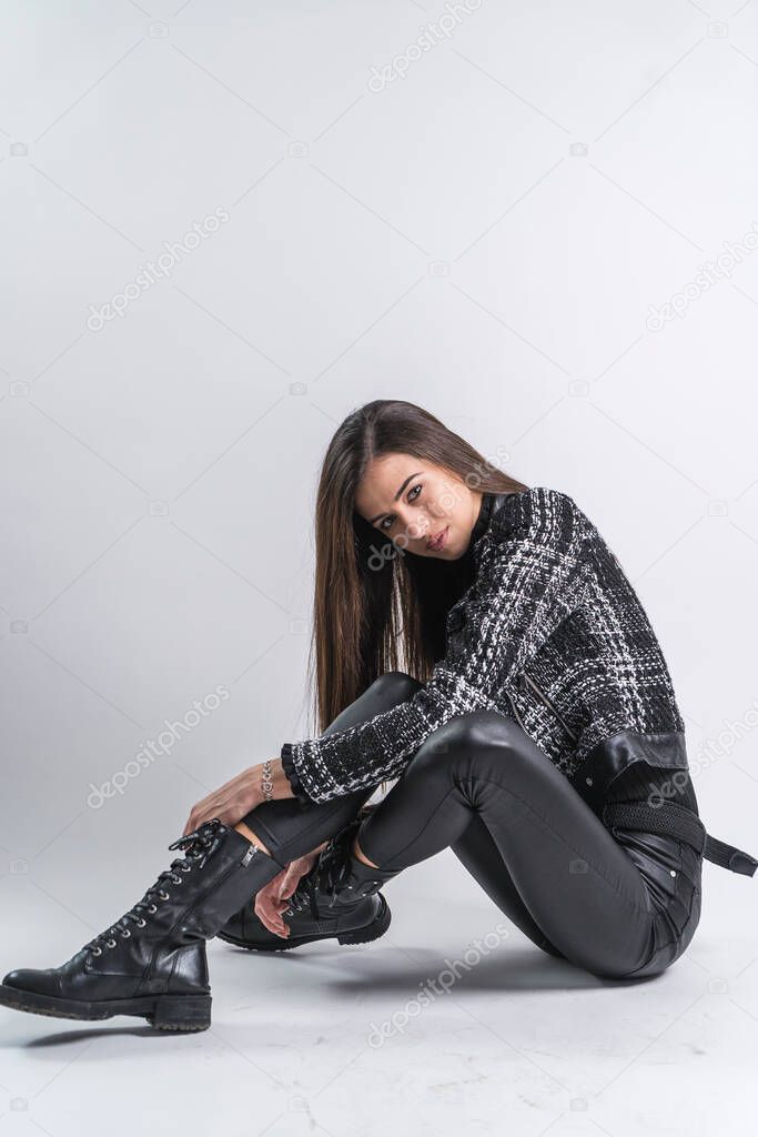 Full body portrait of a female fashion model sitting on whtie background