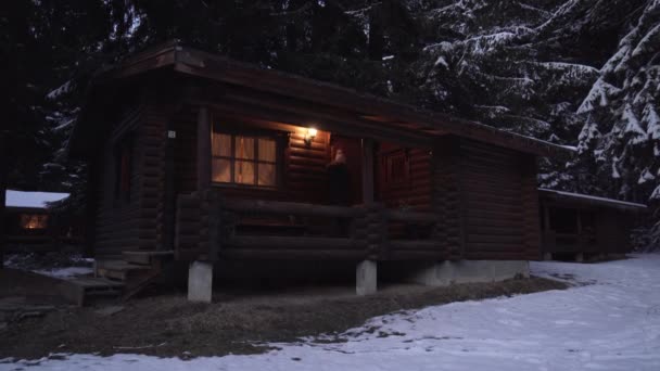 Woman walking out of wooden cabin in cold winter night — Stock Video